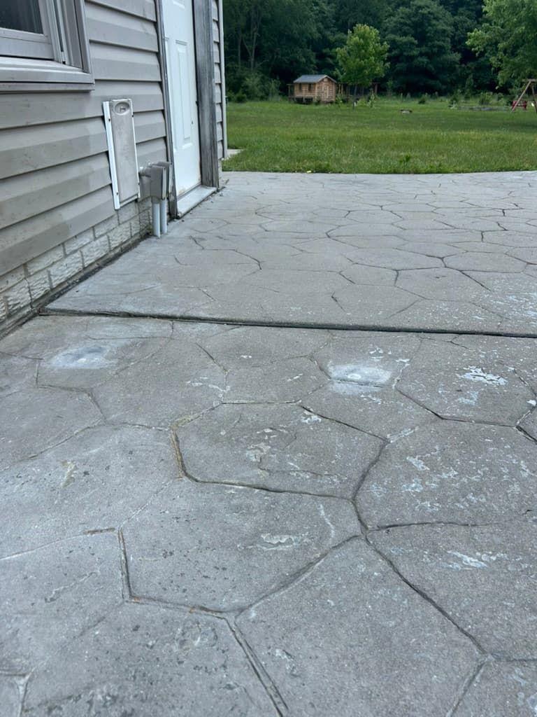 The same stamped patio lifted back to level, flush at the house transition