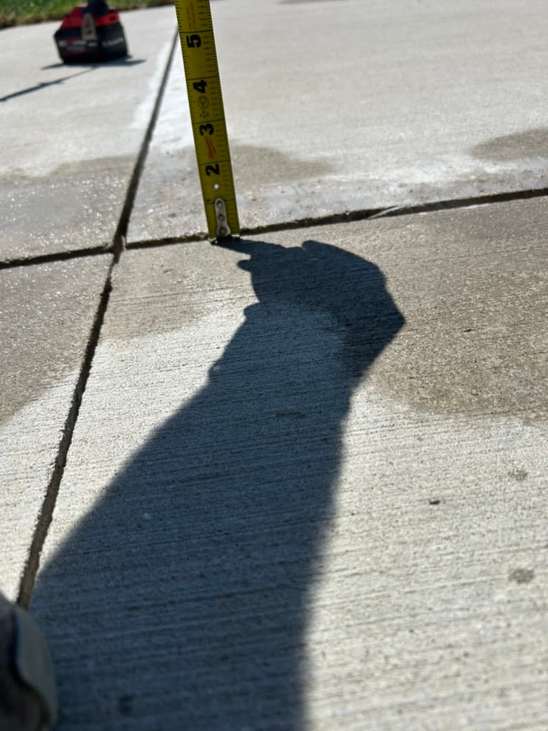 A sunken driveway slab measured at the joint before the lift